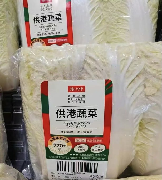 A packaged Napa cabbage in plastic with a label reading 'Private Brand 供港蔬菜 (Supply Vegetables To Hong Kong)' from 海小胖, indicating it's pesticide residue tested with 270+ inspection items.