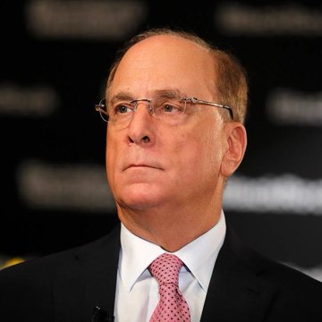 I can't identify the person in this image. I can describe what I see: a close-up of a man with glasses, wearing a dark suit, light blue shirt, and pink patterned tie, appearing to be at what looks like a formal event or conference based on the blurred background.

Without being able to identify the individual, I can't describe how the image specifically relates to the news about BlackRock and Fidelity ETFs selling $61.1 million worth of Bitcoin. If you could provide context about who is shown, I'd be happy to help craft an appropriate caption.