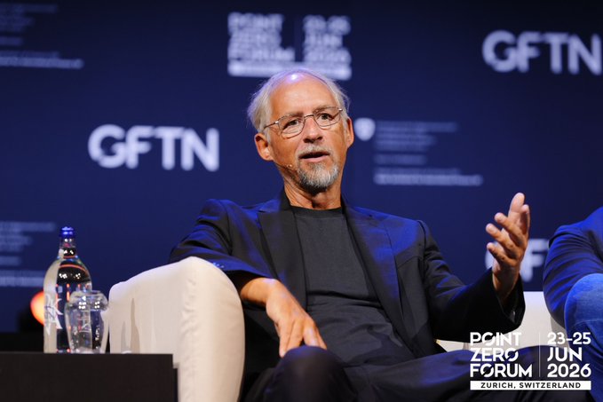 Adam Back speaks at the Point Zero Forum in Zurich (June 23-25, 2026), with the GFTN-branded backdrop visible behind him as he gestures during his panel on Digital Assets at the Crossroads.