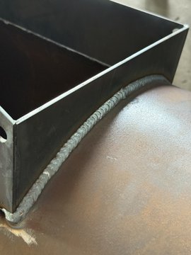 A close-up of a freshly welded square metal tube attached to a rounded, copper-toned surface, showcasing clean, solid weld beads that highlight hands-on fabrication work—fitting the post's theme of stacking (as in, layering physical work and crypto wealth) and "building in web3" with real-world craftsmanship.
