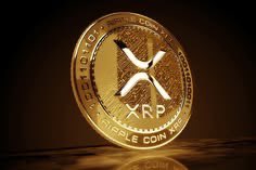 Close-up photograph of a gold-colored physical commemorative coin representing the XRP cryptocurrency (Ripple).