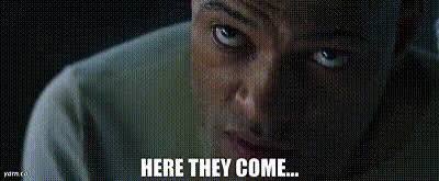 A close-up of Will Smith's face shows him peering through what appears to be prison bars, with the caption "HERE THEY COME..." displayed at the bottom. The image ties to the post "The AI reckoning" by portraying an ominous, approaching threat through Smith's worried, watchful expression as if bracing for something inevitable.