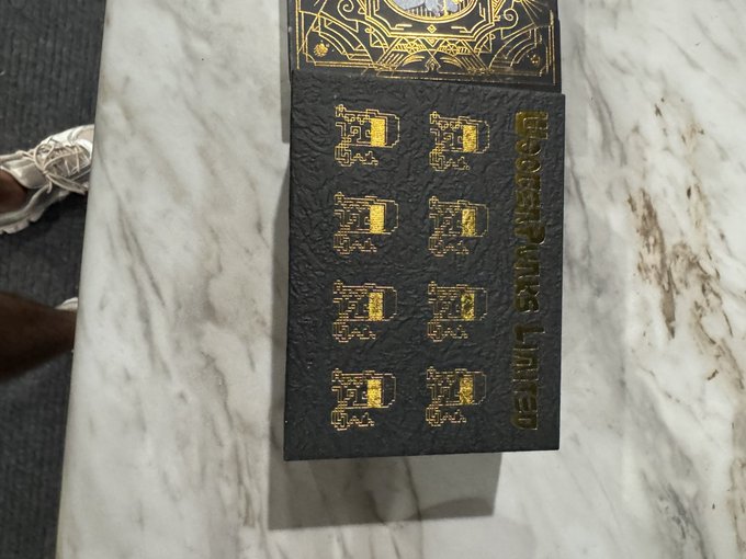 Two stacks of dark-colored cards or tiles with gold decorative borders and pixelated designs on a marble surface.