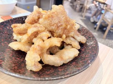 A plate of golden-brown fried calamari rings served on a dark patterned dish at a restaurant.