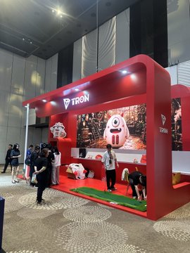 A TRON-branded exhibition stand featuring large cartoon character graphics, set up in a conference hall with attendees nearby.