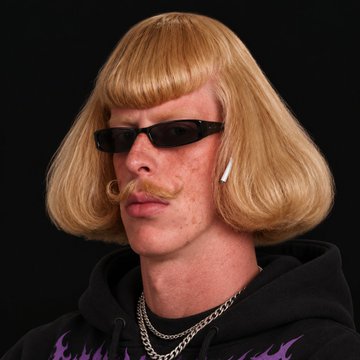 A man wearing a blonde bob wig, dark sunglasses, and a mustache with a silver chain necklace.