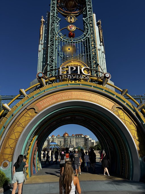 The ornate entrance archway to Epic Universe theme park with visitors walking through the decorated tunnel.
