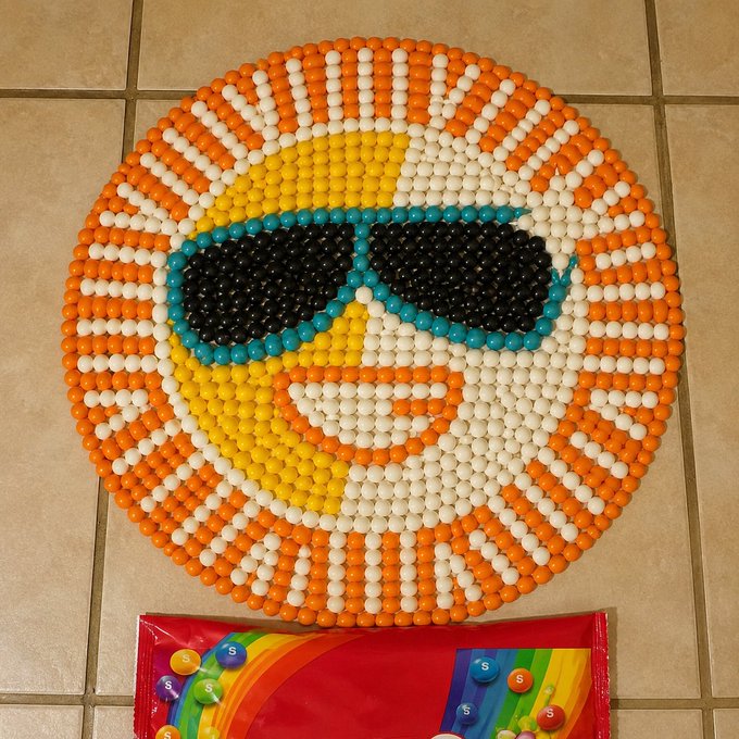 A large smiley face made entirely of orange, white, and yellow candy-coated Skittles wears teal and black sunglasses, sitting above a partially visible rainbow-themed Skittles candy bag on a tile floor—visually representing an "all-in" bet with colorful candy as stakes.

(Note: No text, numbers, tickers, or branded names are clearly legible in the image beyond the generic "S" logos visible on the candy bag's graphic.)