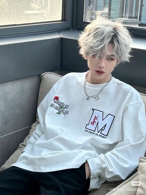 A young person with silver-white hair wearing a white long-sleeve shirt with "M" and "MR.ENJOY DA MONEY" graphics, sitting by a window; a watermark reads "xiaohongshu 558689163".