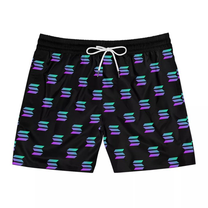 Black board shorts feature a repeating pattern of cyan and purple hexagons with a white drawstring.