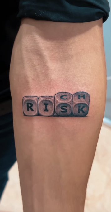 A "RISK" tattoo featuring a redesigned Risk board game logo, fitting the narrator's bold leap from the culinary world into the volatile crypto space.