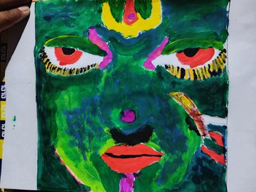 A vibrant, multicolored painted face with striking red eyes and bold green, yellow, and pink hues, held by a hand, likely showcasing the creative vision behind the upcoming MuoriField NFT launch.
