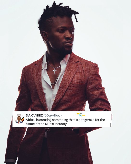 A man in a rust-colored plaid blazer with a cross necklace stands against a white background, with a tweet overlay reading "DAX VIBEZ @Daxvibes · bigeye: Abitex is creating something that is dangerous for the future of the Music industry." The image visually highlights the tweet's claim about Abitex's concerning impact on the music industry, prompting viewers to question what exactly Abitex is creating.