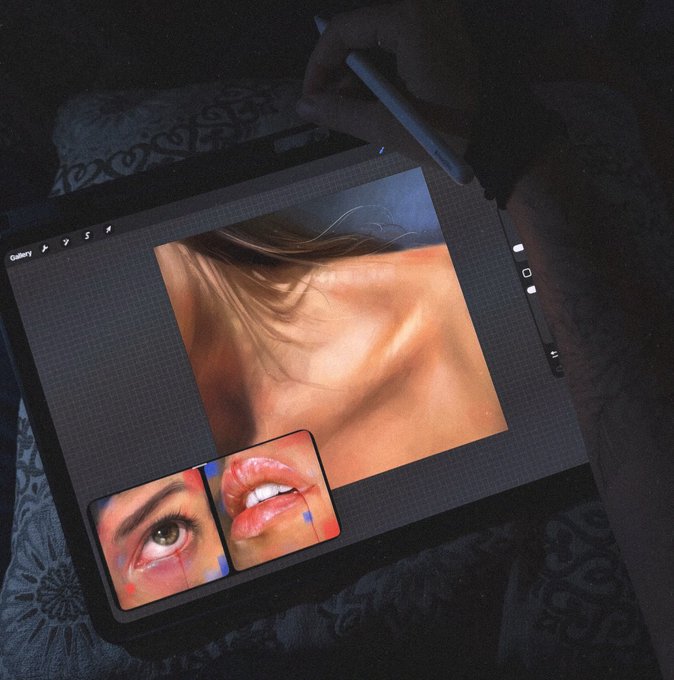 A dark, moody photo showing a hand using a stylus on a tablet displaying digital artwork—close-up portraits of a woman’s face, an eye, and lips—rendered in a painterly style.