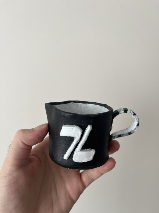 A hand holds a small, hand-built ceramic mug painted black with a white "Z" symbol on its side, physically embodying the Zcash/Zaddr brand referenced in the post. The cup's unfinished, textured appearance reinforces the artisanal, "shielded digital culture made tangible" theme of the accompanying caption.