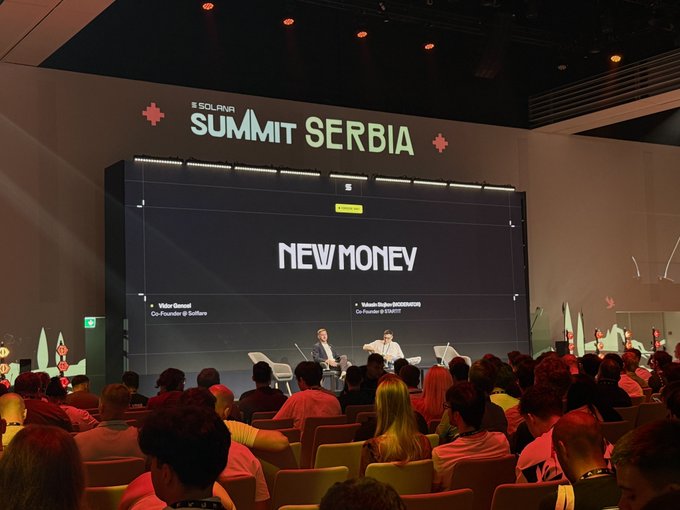 An audience watches a panel discussion at 'SOLANA SUMMIT SERBIA' with the topic 'NEW MONEY' displayed on a large screen, featuring speakers from Solana.