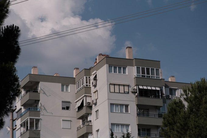 A modern, multi-story residential apartment building with balconies under a partly cloudy sky, illustrating the real-world property that anchors the rental income described in the post. The image grounds the abstract concept of tokenized real estate, visualizing the tangible asset whose lease revenue is said to fund a $BLK buyback recorded on Polygonscan.