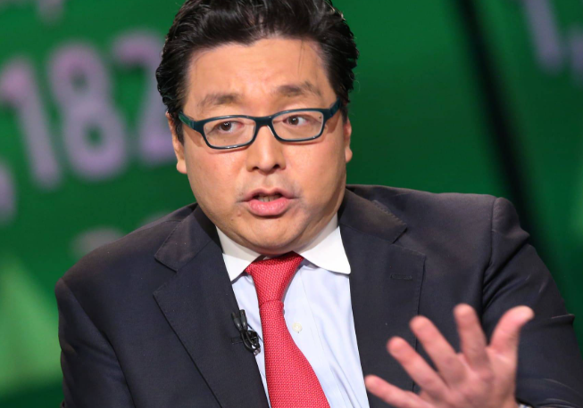 A man in a dark suit, red tie, and glasses speaks animatedly against a green background displaying "1871," with the accompanying post identifying him as Fundstrat analyst Tom Lee issuing a bullish prediction about an imminent explosive surge in Bitcoin and the broader crypto market.