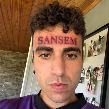 A selfie of a young man with curly hair wearing a purple shirt, with '$ANSEM' digitally overlaid in red text across his forehead.