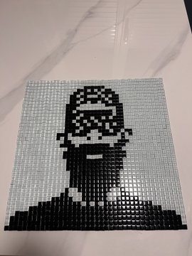 A black and white pixel art portrait of a figure wearing a patterned bandana and sunglasses, made from small mosaic-like tiles on a square canvas.