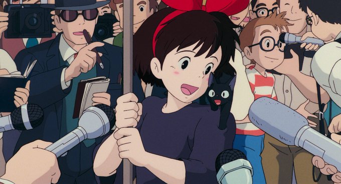 An animated scene featuring a young girl with short brown hair and a red headband, holding a pole, surrounded by reporters with microphones, cameras, and a small black cat on her shoulder.