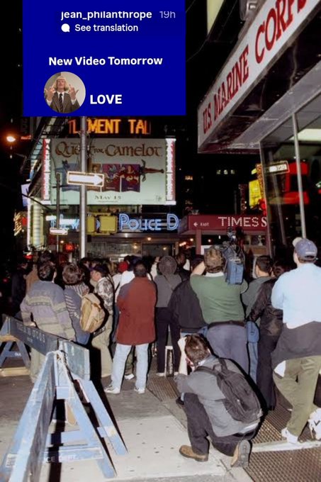 A nighttime street scene shows a crowd gathered near Times Square, with a social media overlay from 'jean_philanthrope' (19h) reading 'New Video Tomorrow' and 'LOVE'.
