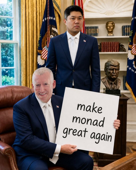 Two men pose in a formal room resembling the Oval Office, with one seated holding a sign reading "make monad great again," echoing a campaign-style slogan while referencing the Monad blockchain/cryptocurrency project.