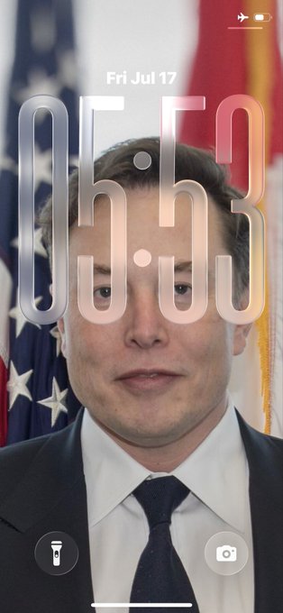 iPhone lock screen wallpaper dated 'Fri Jul 17' featuring a portrait of Elon Musk in a suit with an American flag in the background.