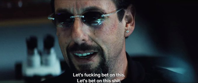A still of Robert Downey Jr. from a movie with sunglasses, smiling and saying 'Let's fucking bet on this. Let's bet on this shit.'