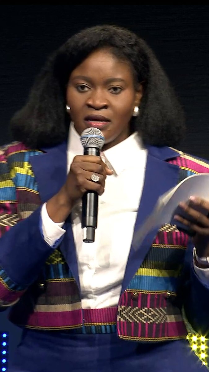 The image features a woman wearing a blue jacket with a colorful pattern standing next to a microphone while speaking into it. The background of the image is black, which contrasts with her outfit and makes her stand out. The caption below the photo reads "During the Freedom Tech track at the 2026 Oslo Freedom Forum, Farida Nabourema, Togolese democracy advocate and founder of the Africa Bitcoin Conference, explains how financial systems can become invisible sanctions against activists, nonprofits, and ordinary citizens". This text is related to the image as it provides context about the event or discussion taking place in the photo.