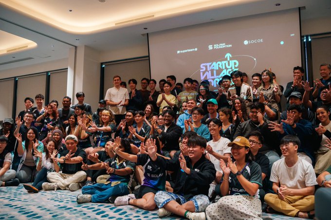 A large group of people pose together at the 'STARTUP BOOTCAMP' event by Superbrand and SOCOE Foundation in Bali, with many wearing matching 'SOLAR' branded shirts and making peace signs.