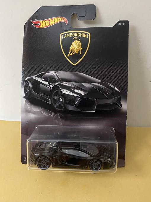 A Hot Wheels die-cast toy car of a Lamborghini in black, still in its original packaging with the Lamborghini logo and age range 4-8 displayed on the card.