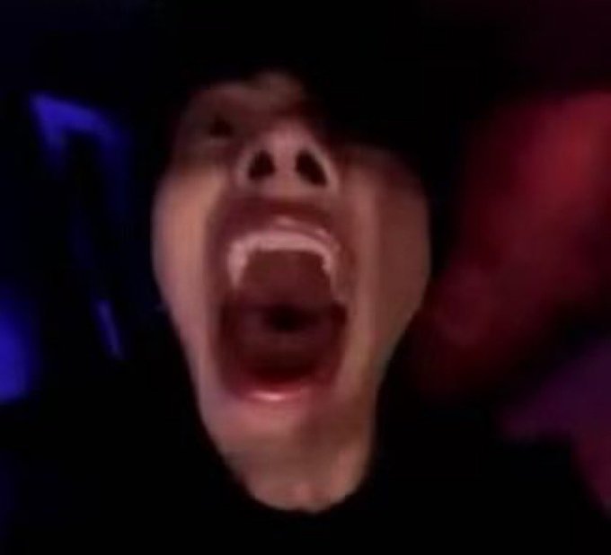 A close-up, blurry image of a person's face screaming with an open mouth.