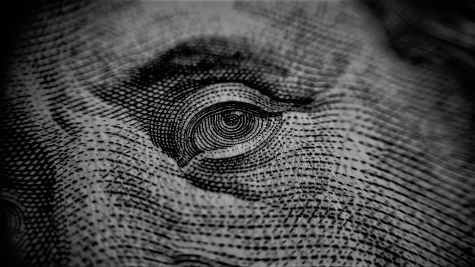 A black and white close-up of the eye on the one hundred dollar bill, showing intricate engraving details.