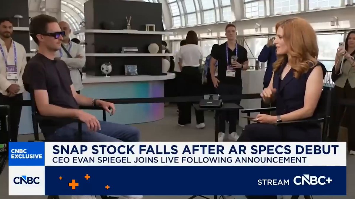 The image features a man sitting down, wearing glasses, with another person standing next to him. They are both dressed in business attire. In front of them, there's an announcement about Snap Stock Falls after AR spects debut. The text on the image reads "Incredible tech Gmonads.com".