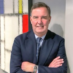 A middle-aged man in a dark suit and patterned tie stands with arms crossed in front of a window with stained glass panels. The image accompanies commentary from Lawrence Lepard, author of "The Big Print," who argues that stablecoins like USDC and USDT are insufficient to support the U.S. Treasury market given their combined supply covers only a small fraction of the $8 trillion in annual debt rollovers.