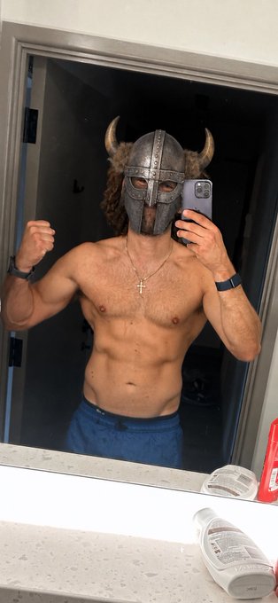 A shirtless, muscular man takes a flexing mirror selfie wearing a horned Viking helmet and a cross necklace, embodying a playful "warrior" vibe as he starts his weekend. The post's "GM X fam" greeting and reference to heading back to the "big smoke" after a short Friday suggest a fun, confident send-off to the crypto community, with $SIVE likely being a token he's watching.