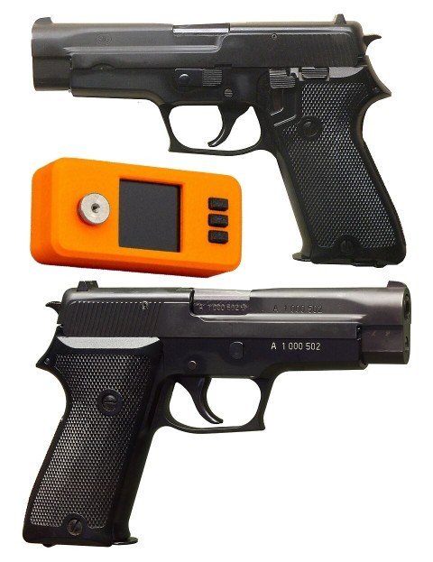 Two black pistols displayed with an orange trigger lock device between them.