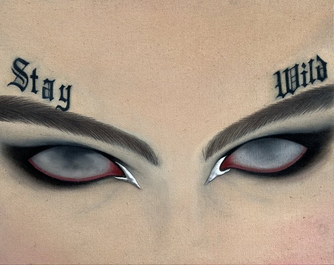 A close-up of eyes featuring dramatic dark eye makeup with the words 'Stay' and 'Wild' tattooed or drawn above the eyebrows in a Gothic font.