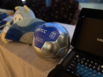 A plush toy resembling a character in blue and white sits next to a silver and blue soccer ball branded with "USTCC" and a crest, alongside a partially visible laptop keyboard. The caption references a humorous "garbage coin shorting technique" attributed to "Grandpa," suggesting the plush may symbolize a quirky, old-school crypto trading strategy amid the USTCC-themed ball.
