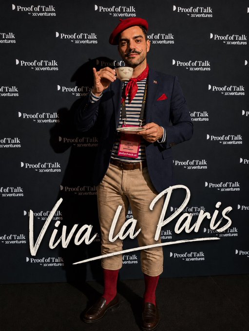 The image features a man dressed in a suit, red hat, and brown pants standing against a black background with a white wall behind him. The man holds a cup of coffee while posing for the picture. The caption of the image reads "Monsieur Pierre-Louis Pouyà d’Étesadie #TerraClassic has never seen such dedication Thank you for your excellent work @LLLsoixante_neuf".