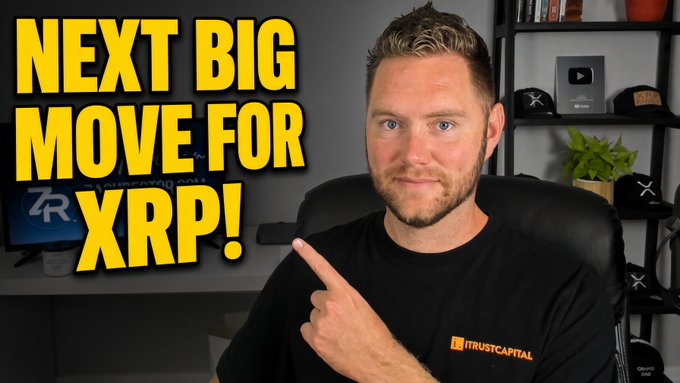A man wearing a black "iTRUSTCAPITAL" t-shirt points toward the camera with large yellow text reading "NEXT BIG MOVE FOR XRP!" displayed beside him. In the background, a shelf holds a YouTube play button award and branded hats, while a monitor shows an XRP logo, reinforcing the video's topic about XRP's upcoming price action.