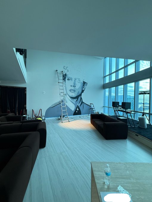 A modern high-rise living space features a large black-and-white mural of David Bowie being painted on the wall, with a ladder and supplies still set up, fitting the post's "great minds think alike" by celebrating the iconoclastic genius of the artist.