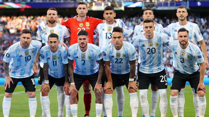 The Argentina national football team poses for a group photo on the pitch, featuring players wearing light blue and white striped jerseys with visible numbers 10, 11, 7, 13, 20, 22, and 3.