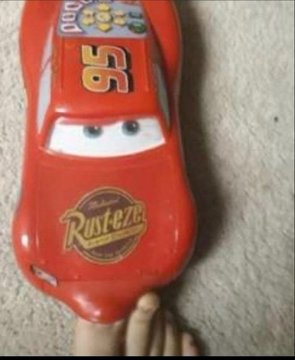 A child's red Lightning McQueen (Cars) themed slipper or sandal featuring the number 95 and Rusteze logo, with a foot visible.