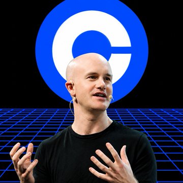 A bald man wearing a black t-shirt speaking on stage, with a large blue and white 'C' logo (Coinbase) displayed on the screen behind him.