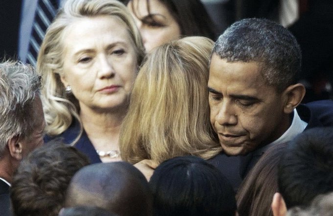 Barack Obama and Hillary Clinton are pictured in a crowd, with Obama leaning in towards a woman while Clinton looks on with a serious expression.