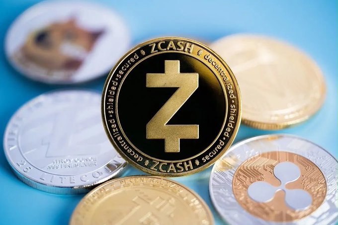 A prominent gold and black Zcash (ZEC) coin is centered among other physical cryptocurrency coins, including Litecoin and XRP, against a blue background. The image visually reinforces the article's announcement of Zcash's "Ironwood" upgrade, highlighting the network's enhanced security and its new "shielded-secured" decentralized features engraved around the coin's edge.