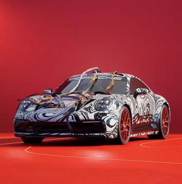A Porsche car wrapped in a gray camouflage pattern with red wheels, displayed on a red surface against a red background.