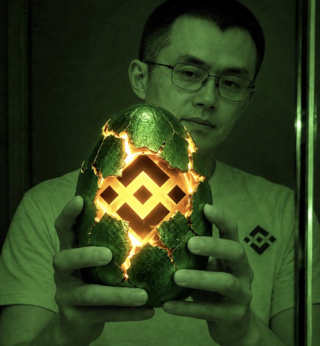 A man wearing glasses holds a glowing egg with the Binance (BNB) logo cracked open to reveal a bright symbol inside, evoking a "hatching" theme. The Binance logo also appears on his shirt, tying the imagery directly to the post's hint that BNB Chain is about to emerge or announce something significant.